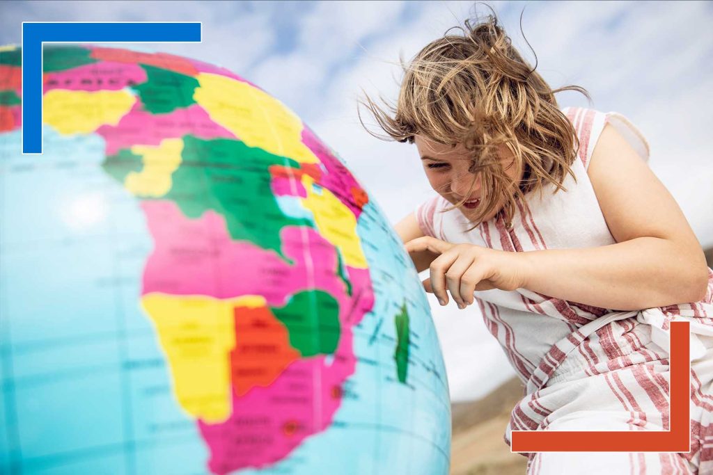 Child pointing at an inflatable globe, symbolizing global reach and offshore developer talent for enterprise innovation projects.